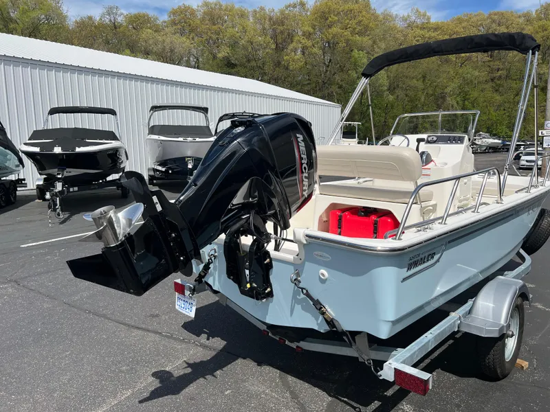 Slide: The Image of 2022 Boston Whaler 150 Montauk boat with outboard motor on trailer, parked outdoors. - 2