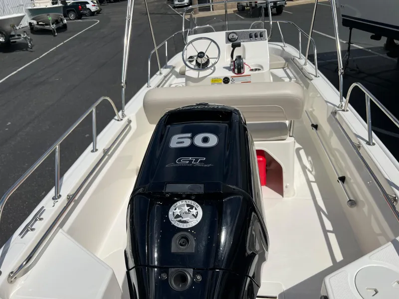 Slide: The Image of 2022 Boston Whaler 150 Montauk boat interior with 60 HP engine, steering console, and seating. - 5