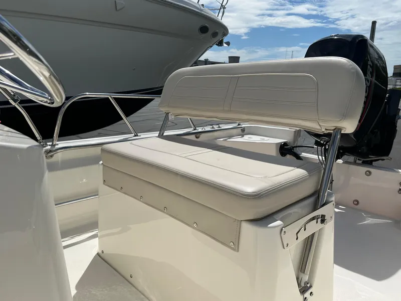 Slide: The Image of 2022 Boston Whaler 150 Montauk boat interior with cushioned seating and railing. - 7