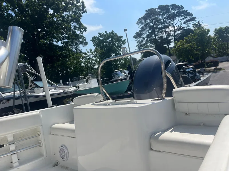 Slide: The Image of 2018 Sea Hunt Triton 225 boat interior with seating and motor, parked outdoors. - 14