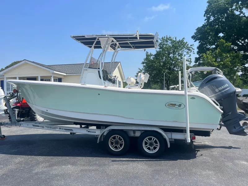 Slide: The Image of 2018 Sea Hunt Triton 225 boat on trailer, parked outdoors, with Yamaha outboard motor. - 2