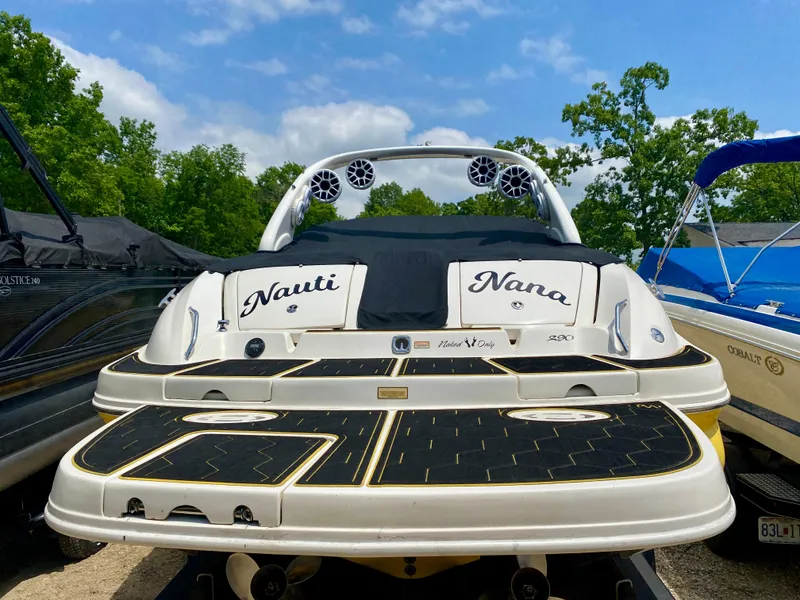 Slide: The Image of 2004 Sea Ray 290 SLX boat with custom "Nauti Nana" name, docked among other boats. - 2
