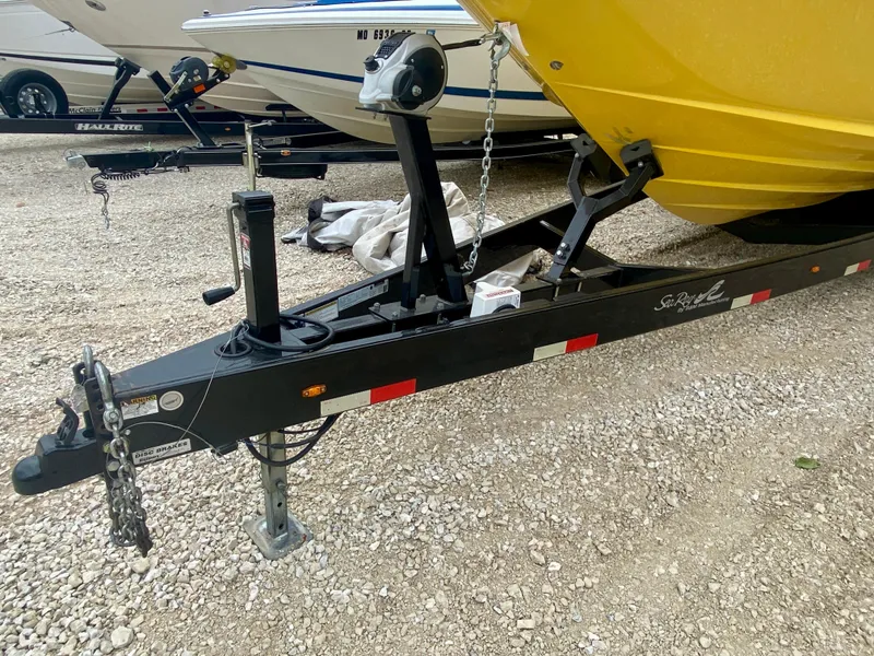 Slide: The Image of 2004 Sea Ray 290 SLX boat on trailer, yellow hull, parked on gravel. - 25