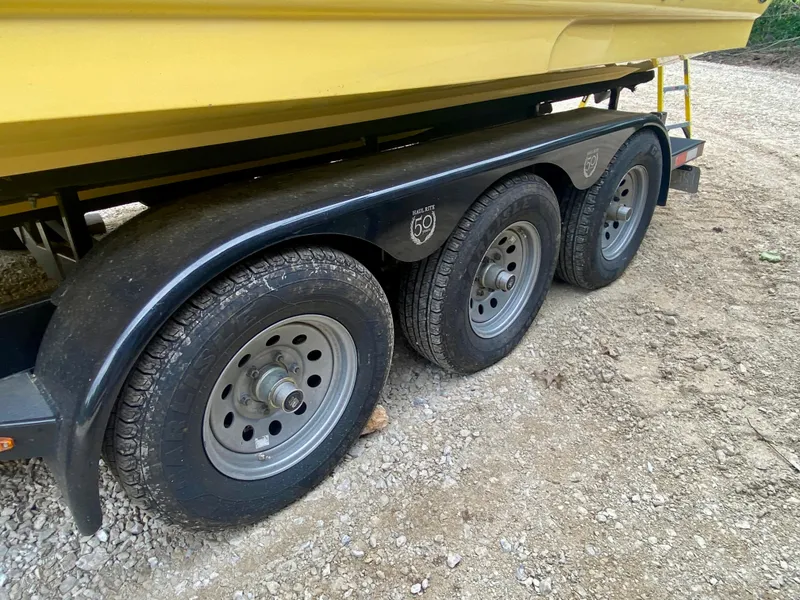Slide: The Image of Trailer with triple axles carrying a yellow 2004 Sea Ray 290 SLX boat. - 26