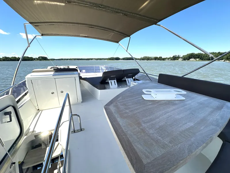 Slide: The Image of Flybridge of 2017 Prestige 500 yacht with seating, table, and canopy on a sunny day. - 1