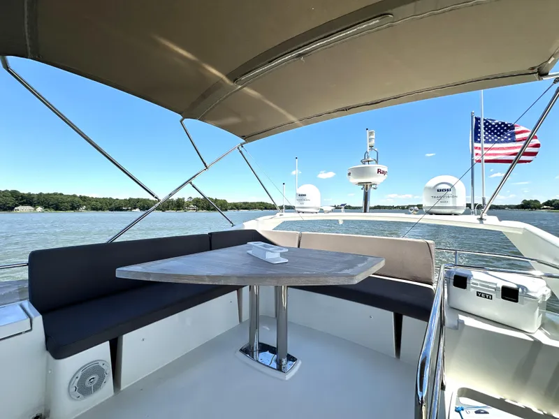 Slide: The Image of Luxurious 2017 Prestige 500 yacht deck with seating, table, and American flag on a sunny day. - 19