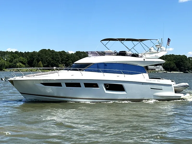 Slide: The Image of 2017 Prestige 500 yacht cruising on a sunny day, surrounded by lush greenery. - 4