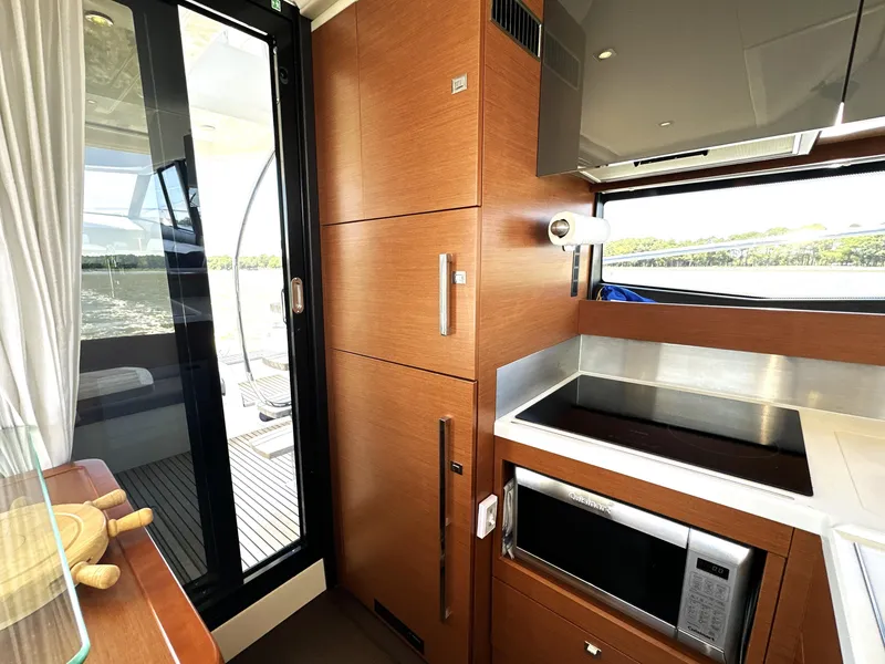 Slide: The Image of Modern kitchen interior on a 2017 Prestige 500 yacht, featuring sleek wood cabinetry and appliances. - 48