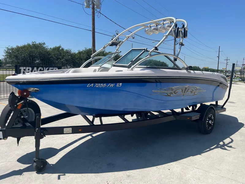 Slide: The Image of 2006 Nautique Air SV-211 Team boat on trailer, blue and white design, sunny day. - 3