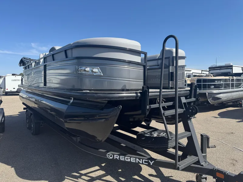 Slide: The Image of 2024 Regency 230 DL3 pontoon boat on trailer in indoor storage facility. - 2
