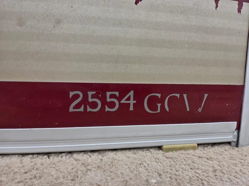 Slide: The Image of 2011 Bennington 2554GCW model nameplate on a red and beige surface. - 10