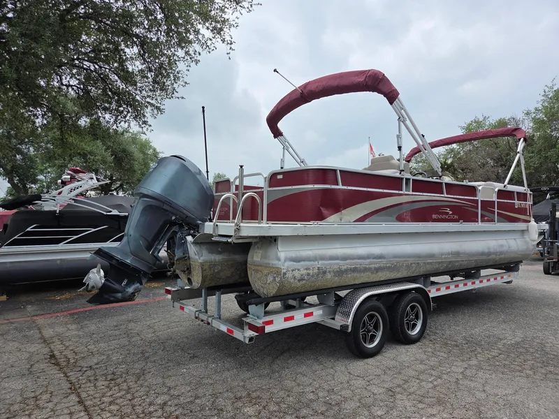 Slide: The Image of 2011 Bennington 2554GCW pontoon boat on trailer, featuring red canopy and outboard motor. - 2