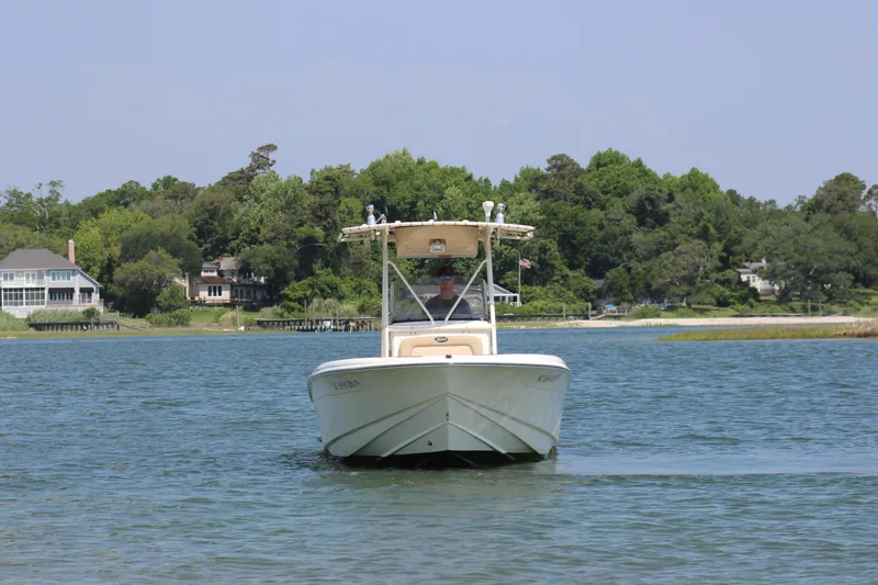 Slide: The Image of 2011 Scout 222 Sportfish boat cruising on a calm lake with lush green shoreline. - 10