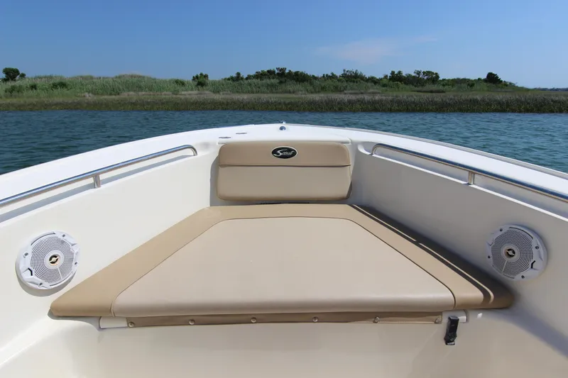 Slide: The Image of 2011 Scout 222 Sportfish boat interior with cushioned seating and speakers, on calm water. - 12