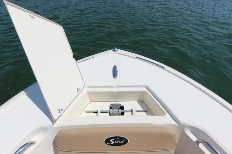 Slide: The Image of 2011 Scout 222 Sportfish boat bow with open storage compartment on calm water. - 13