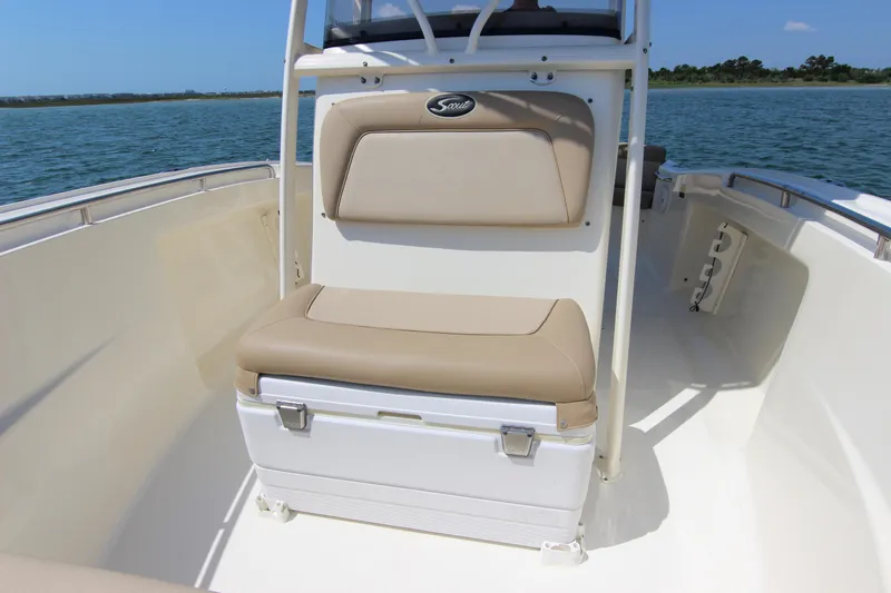 Slide: The Image of 2011 Scout 222 Sportfish boat interior with beige seating and ocean backdrop. - 15