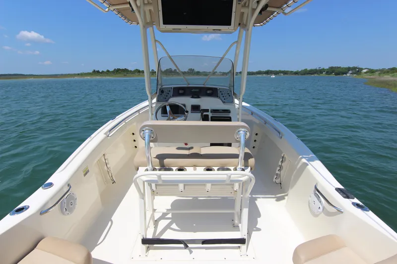 Slide: The Image of 2011 Scout 222 Sportfish boat on calm water, featuring a spacious deck and seating. - 26