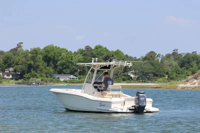 Slide: The Image of 2011 Scout 222 Sportfish boat on a calm lake with lush green shoreline. - 3