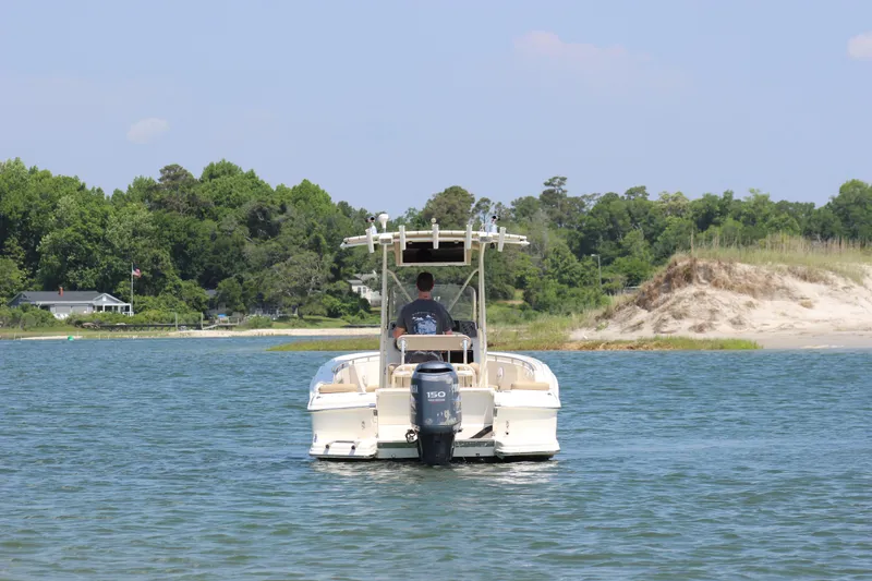 Slide: The Image of 2011 Scout 222 Sportfish boat cruising on a serene lake near a sandy shore. - 4