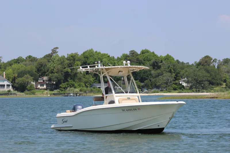 Slide: The Image of 2011 Scout 222 Sportfish boat cruising on a calm lake with lush green shoreline. - 9