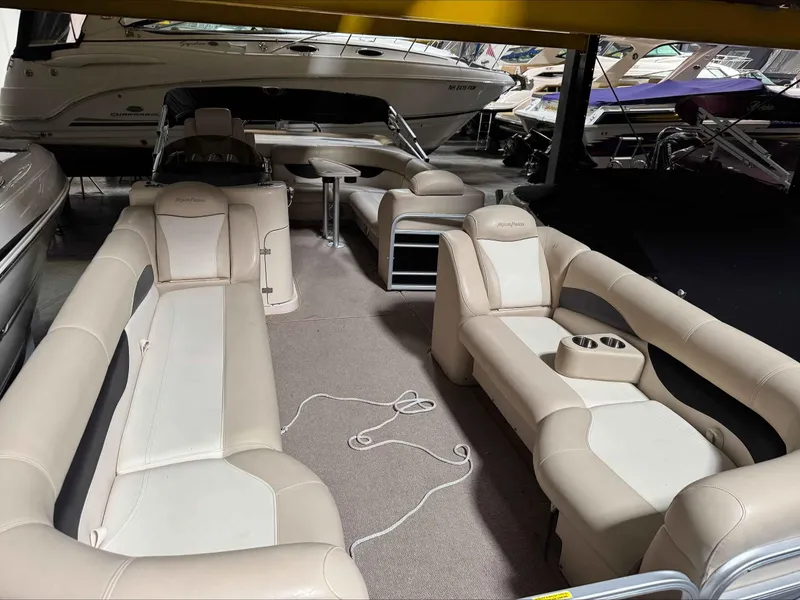Slide: The Image of 2011 Godfrey Aqua Patio 240 pontoon boat interior with beige seating and cup holders. - 10