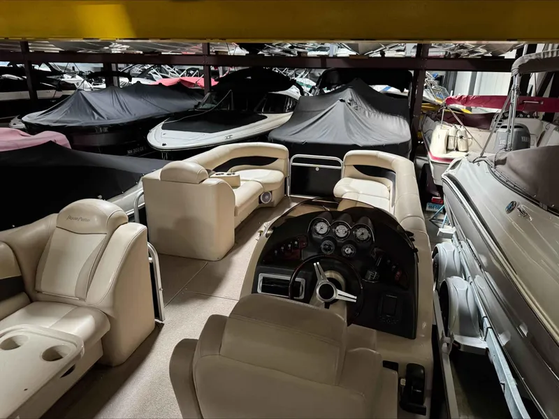 Slide: The Image of 2011 Godfrey Aqua Patio 240 pontoon boat interior in storage, surrounded by covered boats. - 4