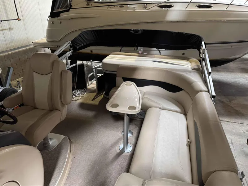 Slide: The Image of 2011 Godfrey Aqua Patio 240 interior with beige seating and table in a boat garage. - 5