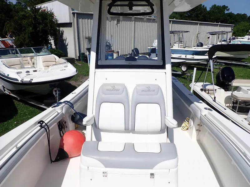 Slide: The Image of 2020 Regulator 23 boat interior with dual seats and console, docked among other boats. - 16