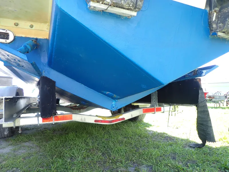 Slide: The Image of 2020 Regulator 23 boat hull on trailer, blue paint, grassy background. - 20