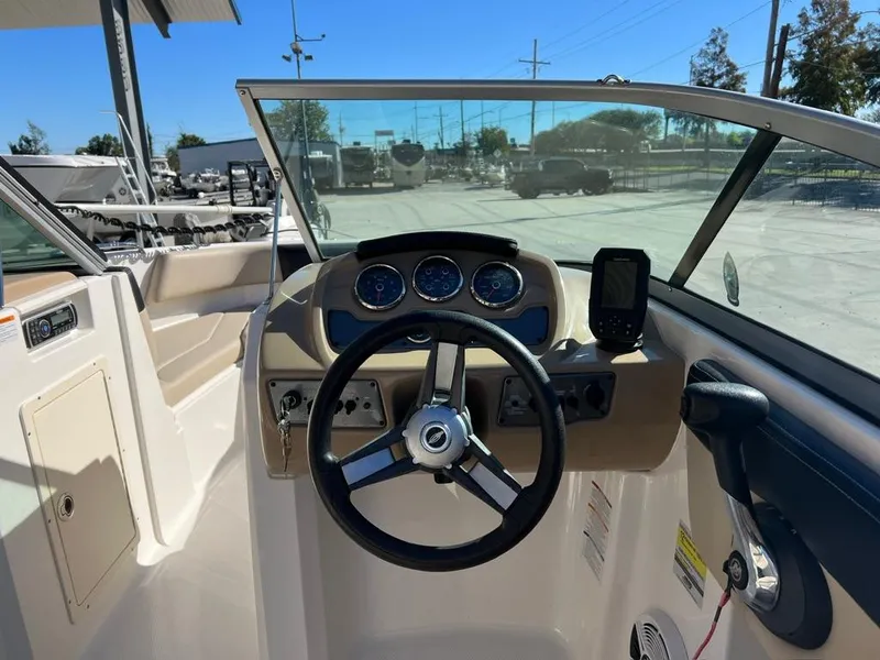 Slide: The Image of 2017 Chaparral H20 boat dashboard with steering wheel and gauges in a marina setting. - 6