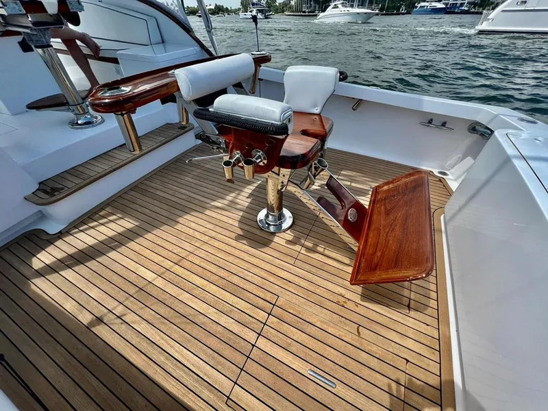 Slide: The Image of 1999 Gamefisherman 34 Express boat with teak deck and fishing chair, docked on calm waters. - 24