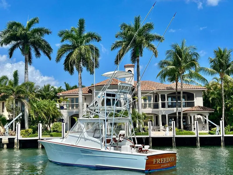 Slide: The Image of 1999 Gamefisherman 34 Express boat docked near a luxurious waterfront mansion with palm trees. - 28