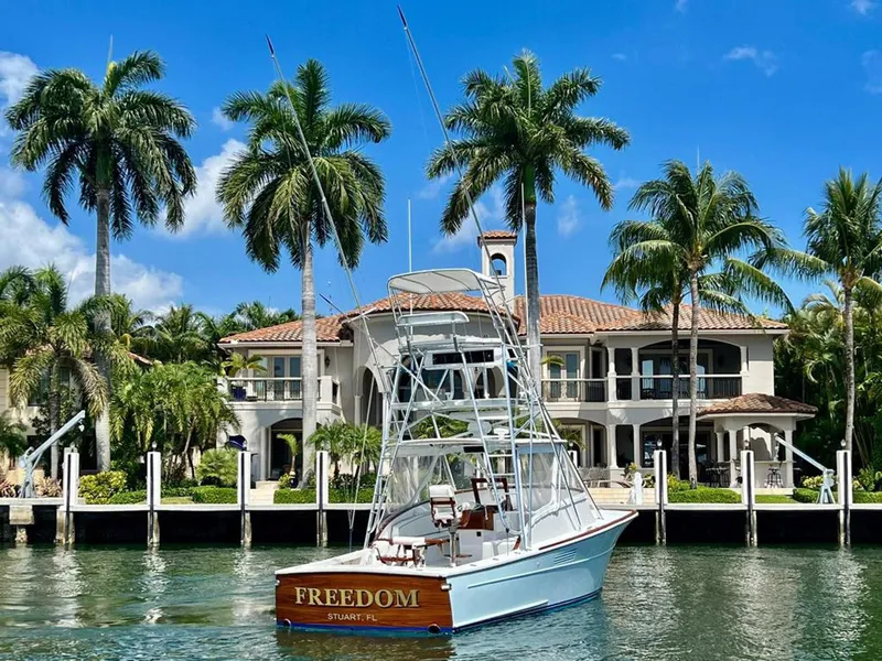 Slide: The Image of 1999 Gamefisherman 34 Express boat named "Freedom" docked near a luxurious waterfront mansion. - 29