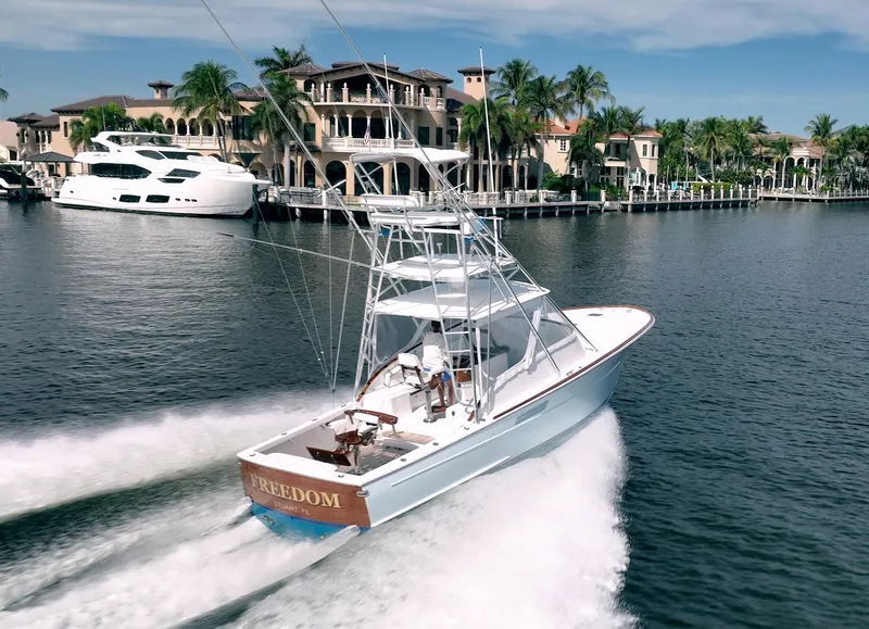 Slide: The Image of 1999 Gamefisherman 34 Express yacht cruising near luxury waterfront homes. - 3