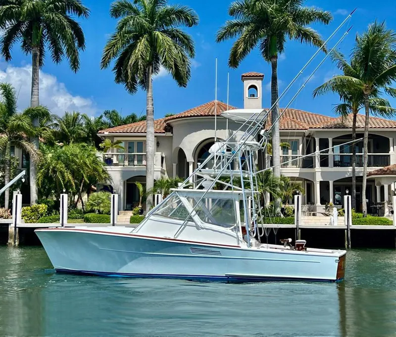Slide: The Image of 1999 Gamefisherman 34 Express boat docked near a luxurious waterfront mansion with palm trees. - 30