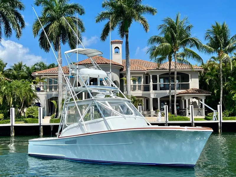 Slide: The Image of 1999 Gamefisherman 34 Express boat docked near a luxurious waterfront mansion with palm trees. - 31