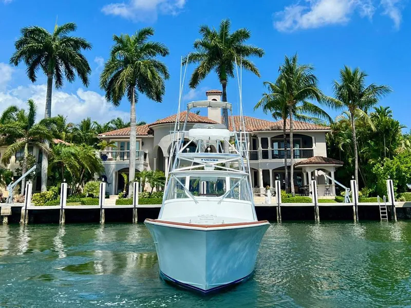 Slide: The Image of 1999 Gamefisherman 34 Express boat docked by a luxurious waterfront mansion with palm trees. - 32