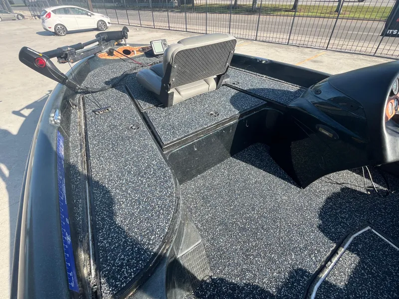 Slide: The Image of 1998 Triton Tr-17 boat interior with seating and control panel, parked outdoors. - 9