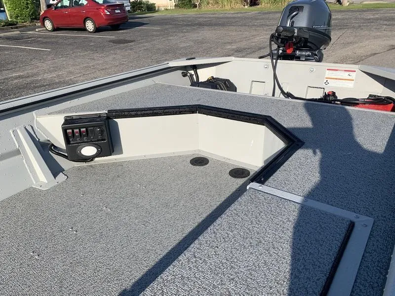 Slide: The Image of 2025 SeaArk DXS 1548 DKLD boat interior with motor, parked in a lot. - 11