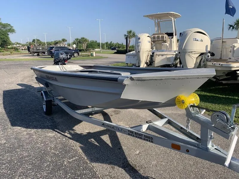 Slide: The Image of 2025 SeaArk DXS 1548 DKLD boat on trailer, parked outdoors in a marina setting. - 6