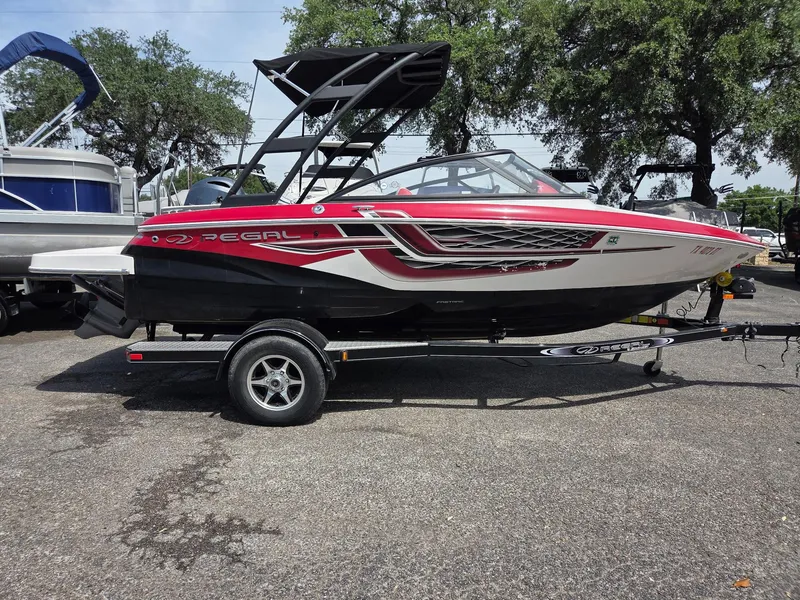 Slide: The Image of 2017 Regal 1900 ES Bowrider boat on trailer, red and white design, parked outdoors. - 5