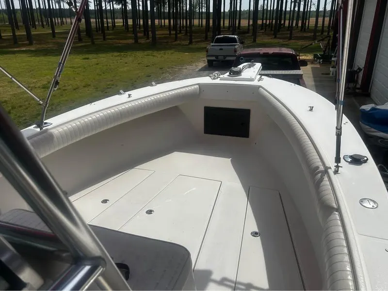 Slide: The Image of 1998 Regulator 26 Classic boat with spacious deck, parked near trees and vehicles. - 4