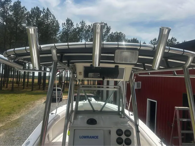 Slide: The Image of 1998 Regulator 26 Classic boat with T-top and Lowrance electronics, parked near trees and a red building. - 5