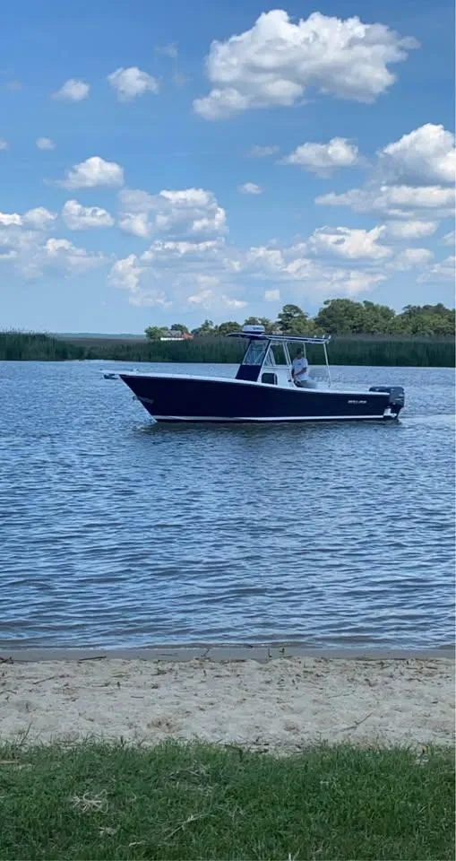 Slide: The Image of 1998 Regulator 26 Classic boat on calm water under a blue sky with clouds. - 6