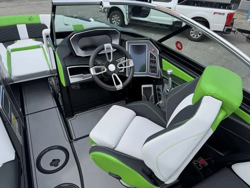 Slide: The Image of 2021 MasterCraft X24 boat interior with green and white seating, modern dashboard, and steering wheel. - 11