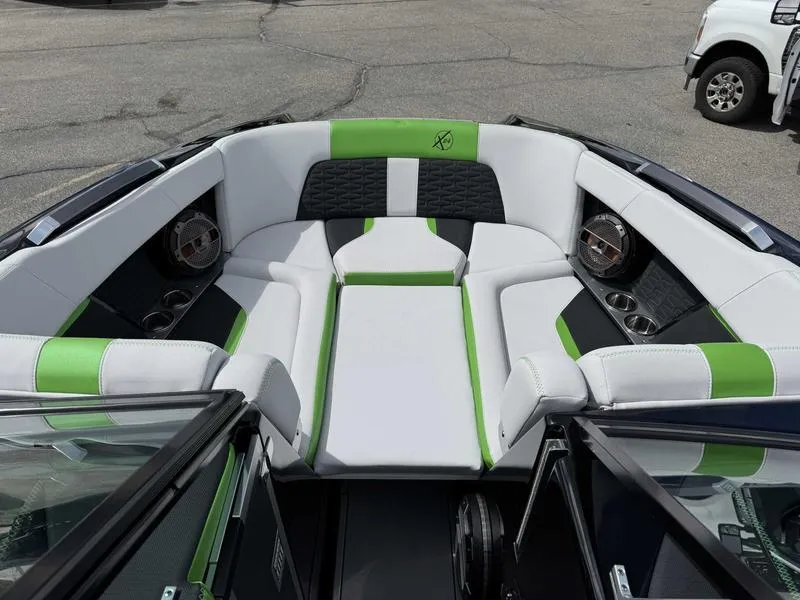 Slide: The Image of 2021 MasterCraft X24 boat interior with green and white seating, featuring cup holders and speakers. - 14