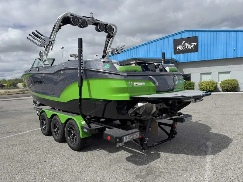Slide: The Image of 2021 MasterCraft X24 boat on trailer, green and black, parked outside Prestige building. - 6