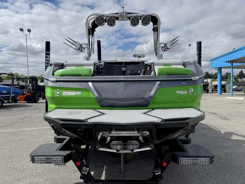 Slide: The Image of 2021 MasterCraft X24 boat, green exterior, rear view, parked outdoors under cloudy sky. - 7