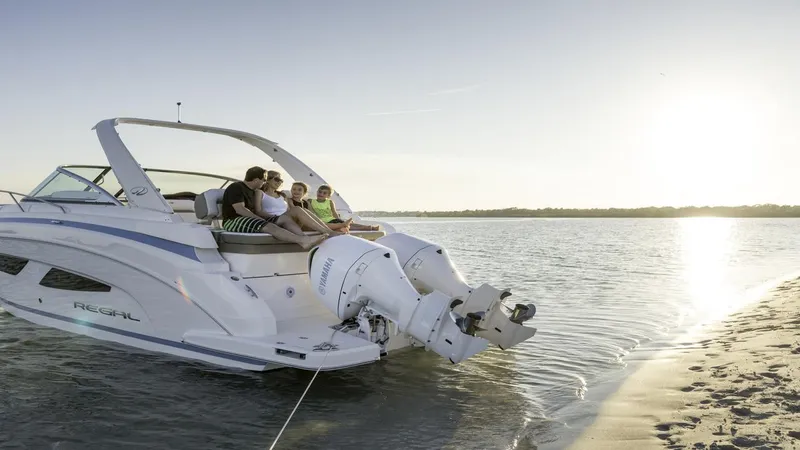 Slide: The Image of 2026 Regal 33 XO boat anchored on a serene beach at sunset. - 2