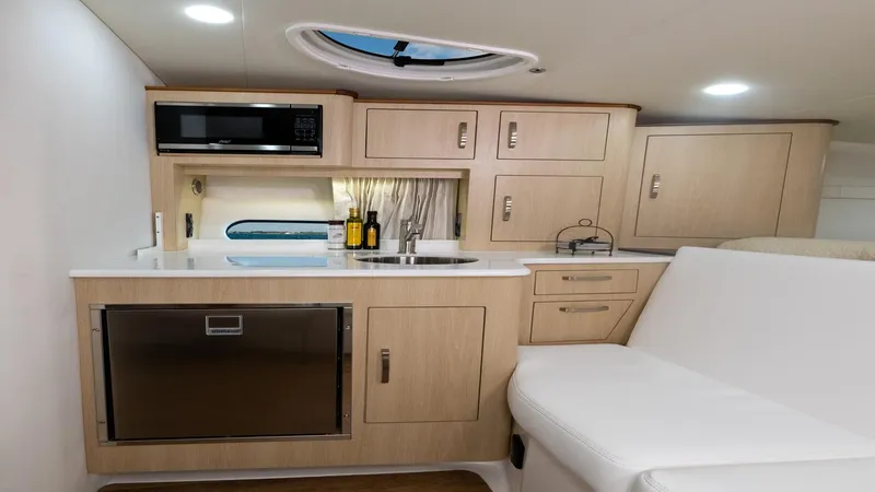 Slide: The Image of 2026 Regal 33 XO yacht interior with modern kitchenette, featuring light wood cabinetry and sleek appliances. - 39
